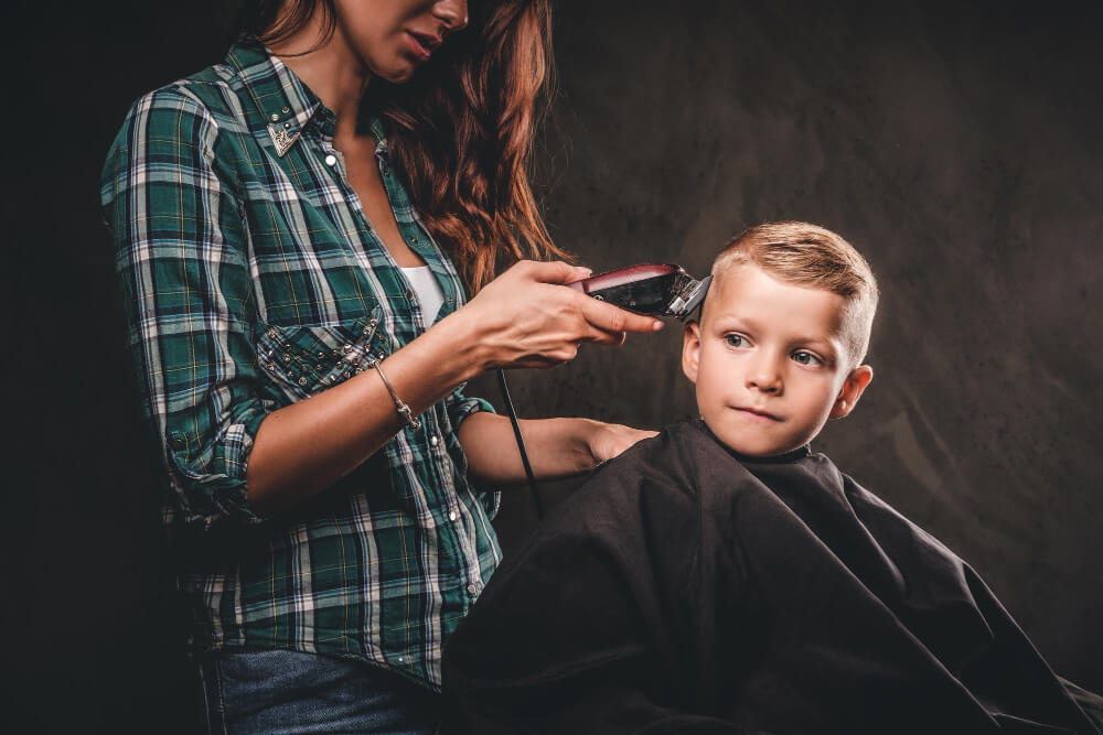 Toddler boy having a Side Sweep from laddy barber.