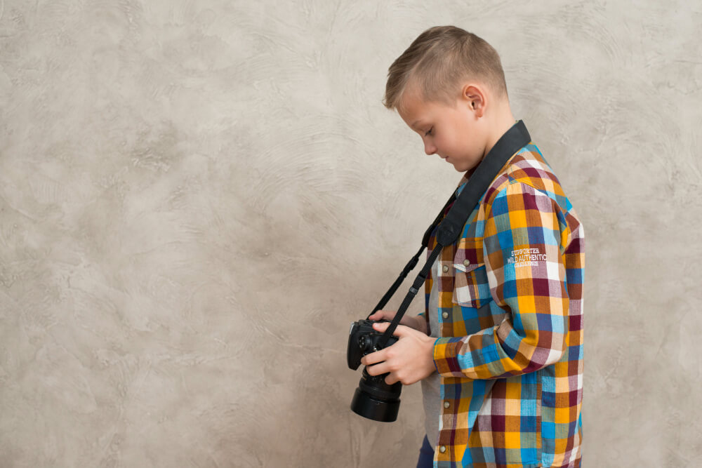 A boy ready for a picture with Slicked-Back Fade haircut having camera in hand
